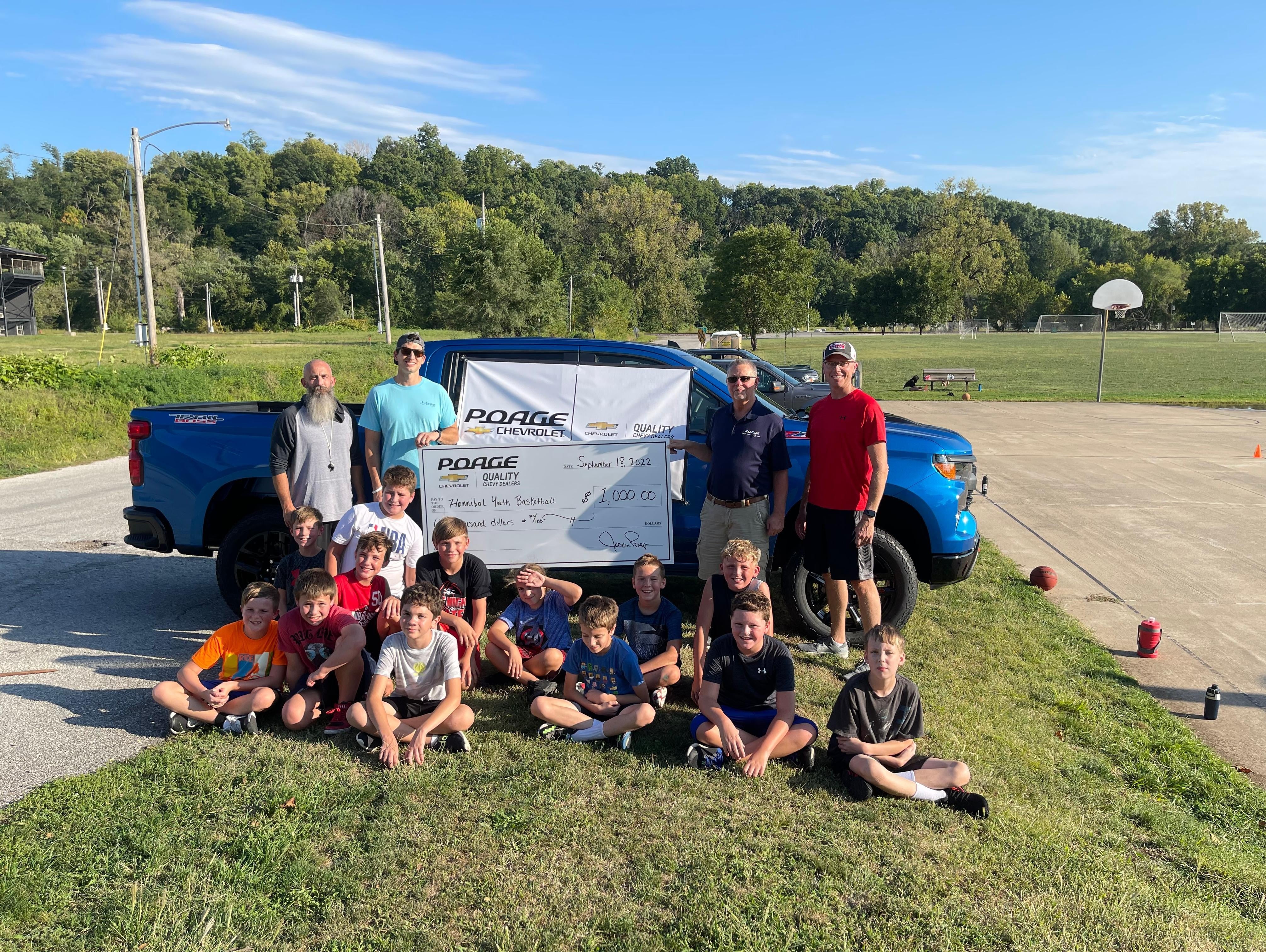Poage Chevrolet Buick members holding giant check with community members