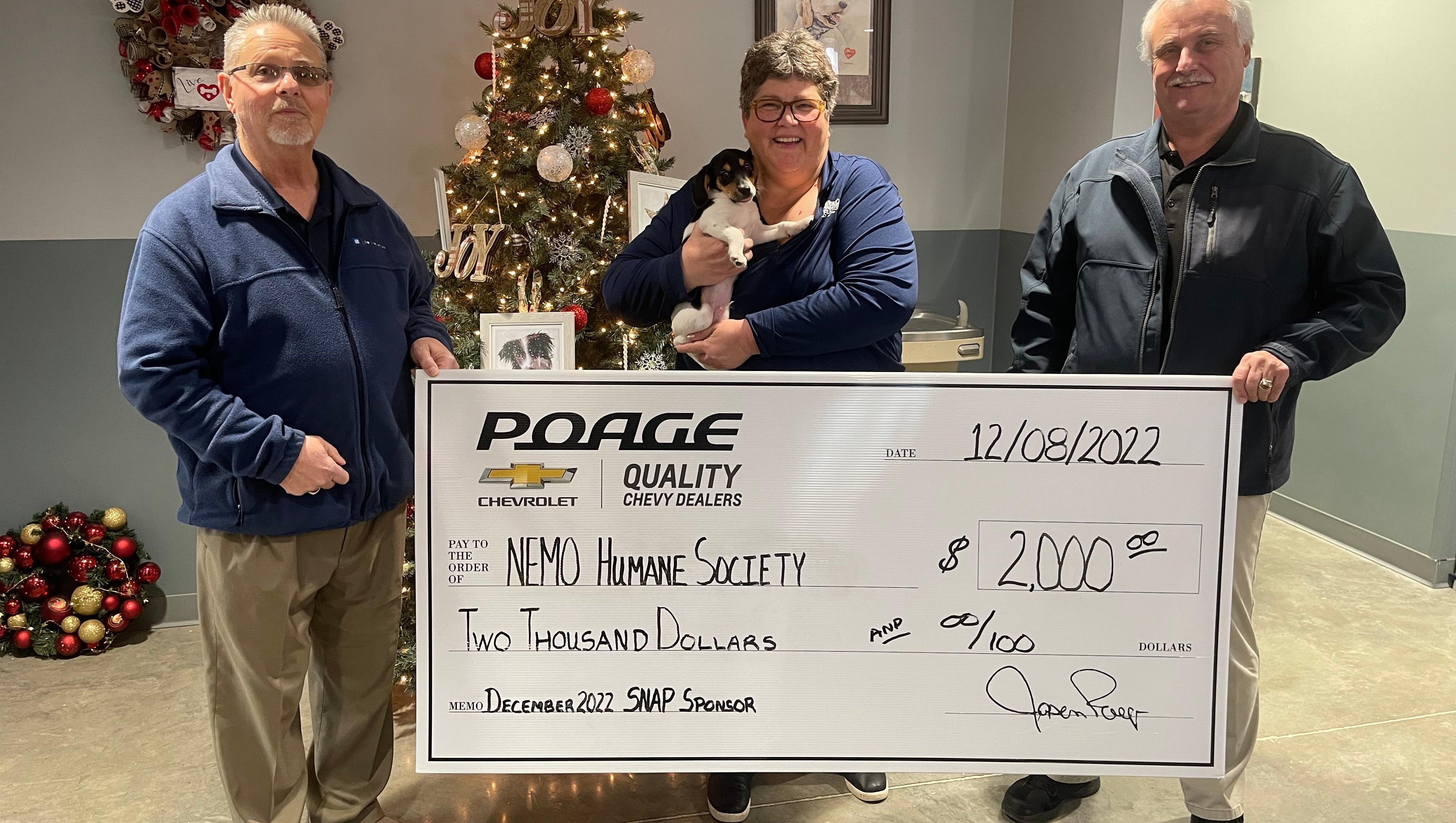 Poage Chevrolet Buick members holding giant check with community members
